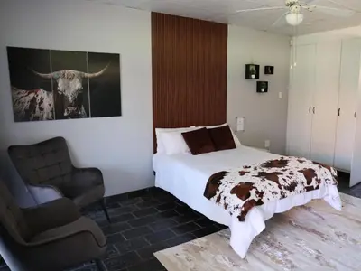 a bedroom with a bed and a chair in it at Malembe Lodge in Midrand