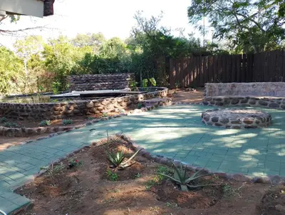 a patio with a bench and a stone wall at TarRoadEnds in Hoedspruit