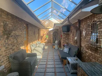 an outdoor patio with couches and a glass roof at Dobbs Lodge in Centurion