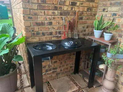 a black table in front of a brick wall with plants at Dobbs Lodge in Centurion