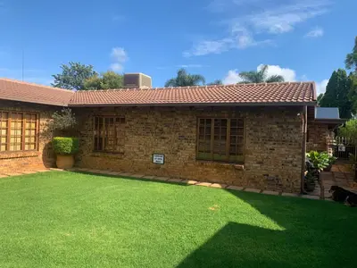 a brick house with a lawn in front of it at Dobbs Lodge in Centurion