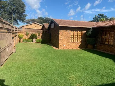 a yard with green grass next to a house at Dobbs Lodge in Centurion