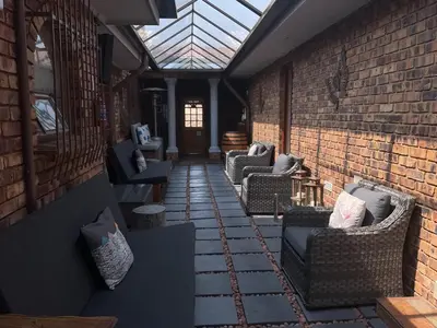 an outdoor patio with chairs and a glass roof at Dobbs Lodge in Centurion