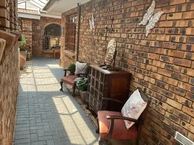 a patio with two chairs and a brick wall at Dobbs Lodge in Centurion