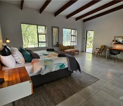 a bedroom with a large bed and a living room at Riverside Self-Catering Accommodation