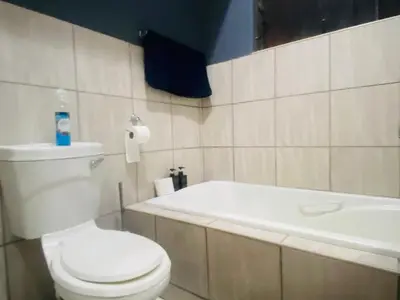 a bathroom with a white toilet and a bath tub at A spacious 2bedrooms apartment in the heart of Kempton Park in Kempton Park