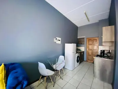 a kitchen with two white chairs and a refrigerator at A spacious 2bedrooms apartment in the heart of Kempton Park in Kempton Park