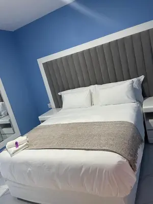 a bedroom with a large white bed with a blue wall at Lupulo luxury boutique in Thohoyandou