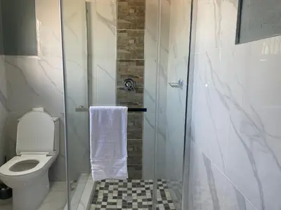 a bathroom with a toilet and a glass shower at Lupulo luxury boutique in Thohoyandou