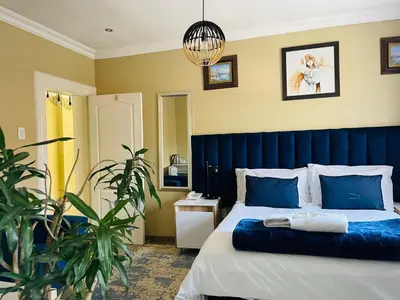 a bedroom with a bed with a blue headboard at Henry George Hotel in Pretoria