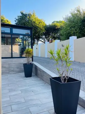 two black pots with plants in them on a patio at Henry George Hotel in Pretoria
