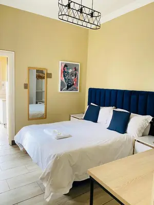 a bedroom with a large bed with a blue headboard at Henry George Hotel in Pretoria