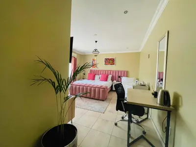 a living room with a pink couch and a desk at Henry George Hotel in Pretoria