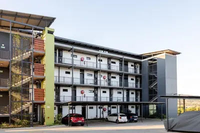 an apartment building with cars parked in a parking lot at Chawal Stays Green Valley 1 in Nelspruit