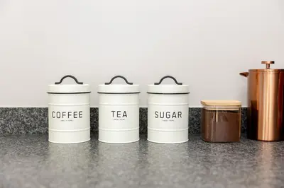 a row of coffee tea and sugar containers on a counter at Chawal Stays Green Valley 1 in Nelspruit