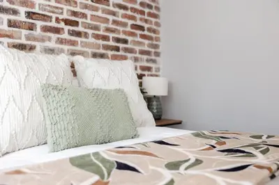 a bed with pillows and a brick wall at Chawal Stays Green Valley 1 in Nelspruit