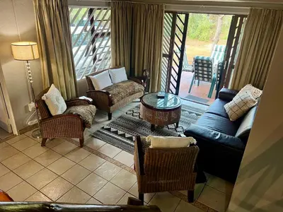 a living room with a couch and chairs and a table at Tranquil Bush Cottage at Kruger in Marloth Park
