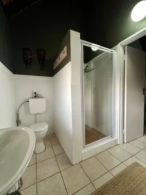 a bathroom with a shower and a toilet and a sink at Tranquil Bush Cottage at Kruger in Marloth Park
