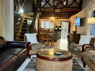 a living room with leather couches and a table at Tranquil Bush Cottage at Kruger in Marloth Park
