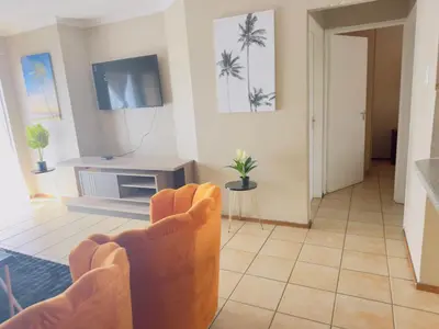 a living room with a chair and a tv at Luxury two bedrooms apartment in Witbank overnight accommodation in Witbank