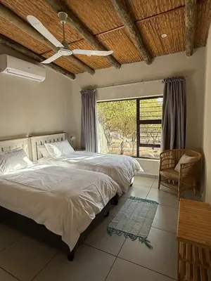 a bedroom with a bed with a ceiling fan and a window at Ingonyama Rest in Marloth Park