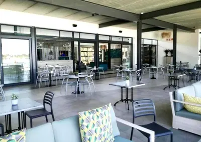a restaurant with tables and chairs and windows at Beach-Style Modern Apt at The Blyde in Pretoria