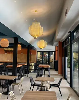 a restaurant with tables and chairs and chandeliers at Beach-Style Modern Apt at The Blyde in Pretoria
