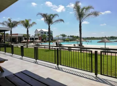 a view of the pool at a resort with palm trees at Beach-Style Modern Apt at The Blyde in Pretoria