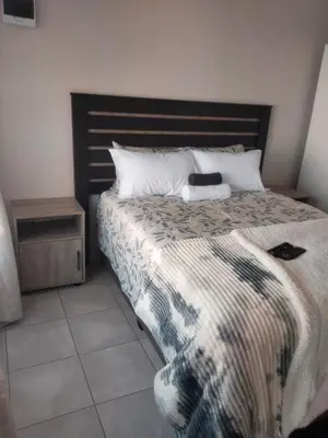 a bedroom with a bed with a black and white blanket at Rasesa Guesthouse Block V in Soshanguve