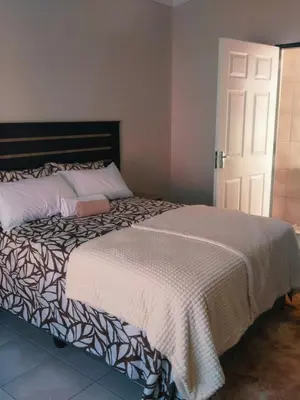 a bedroom with a large bed with a black and white blanket at Rasesa Guesthouse Block V in Soshanguve