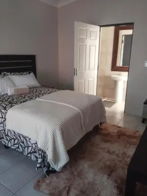 a bedroom with a large bed and a bathroom at Rasesa Guesthouse Block V in Soshanguve
