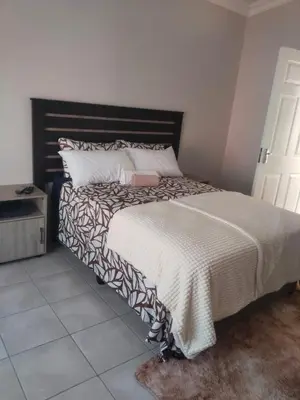 a bedroom with a large bed with a black headboard at Rasesa Guesthouse Block V in Soshanguve