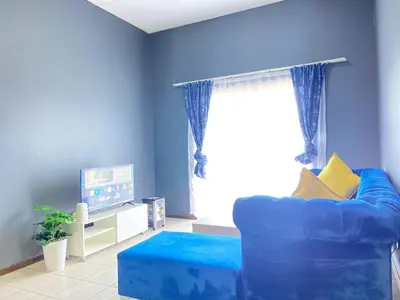 a blue living room with a blue couch and a television at A spacious 1bedroom apartment in the heart of Kempton Park in Kempton Park