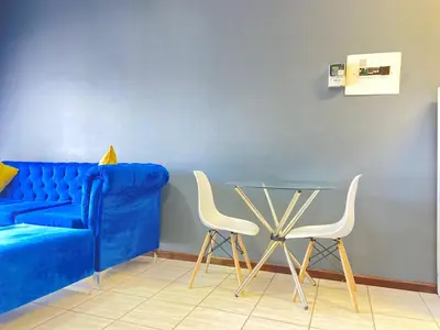 a blue couch with two white chairs and a glass table at A spacious 1bedroom apartment in the heart of Kempton Park in Kempton Park