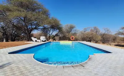 a swimming pool with blue water in a yard at Private Lodge at Vaalkop Dam Reserve in Beestekraal