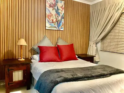 a bedroom with a large bed with red pillows at Little Swift 1 in Secunda