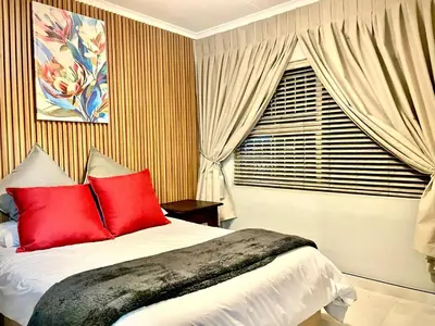 a bedroom with a bed with red pillows and a window at Little Swift 1 in Secunda