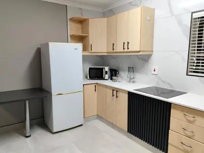 a kitchen with a white refrigerator and wooden cabinets at Little Swift 1 in Secunda