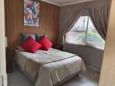 a bedroom with a bed with red pillows and a window at Little Swift 1 in Secunda