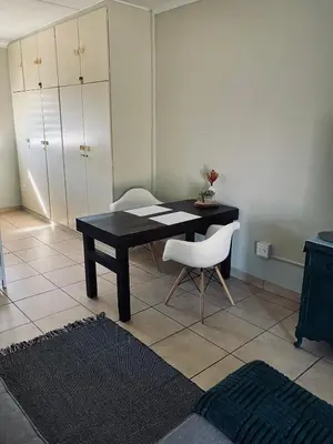a dining room with a black table and white chairs at Willow Cottage in Evander