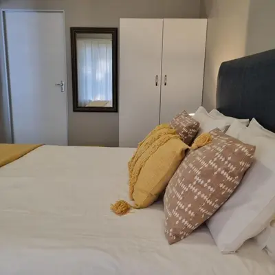 a bed with three pillows on top of it at Kruin suite in Pretoria