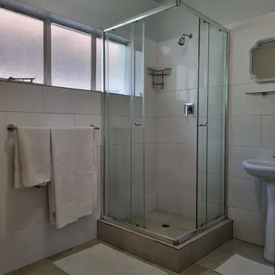 a bathroom with a glass shower and a sink at Kruin suite in Pretoria