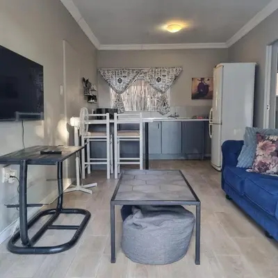 a living room with a blue couch and a kitchen at Kruin suite in Pretoria