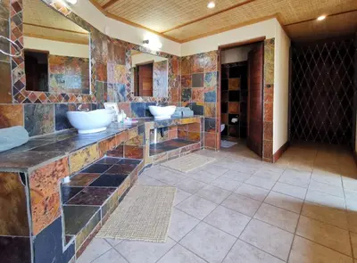 a bathroom with two sinks on a stone wall at Buffalo Game Lodge in Warmbaths