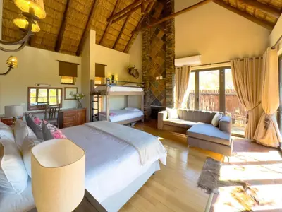 a bedroom with a large bed and a living room at Buffalo Game Lodge in Warmbaths