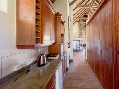a kitchen with wooden cabinets and a tile floor at Buffalo Game Lodge in Warmbaths