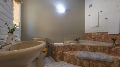 a bathroom with a tub and a toilet and a sink at Stay at Percy2 in Nelspruit