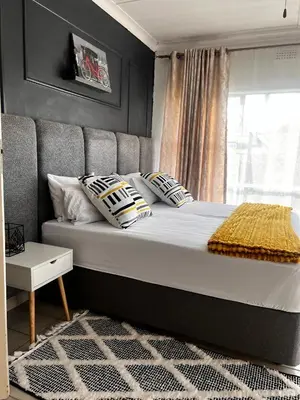 a bedroom with a bed with pillows and a window at Pebetzel Luxury Home XX2 in Kempton Park