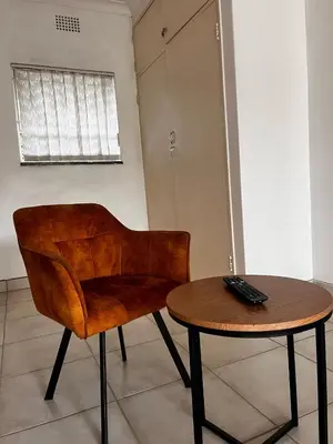 a wooden chair and a table with a remote control on it at Pebetzel Luxury Home XX2 in Kempton Park