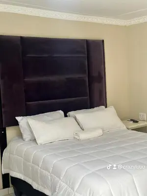 a bed with a large black headboard and white pillows at Rose's Lodge